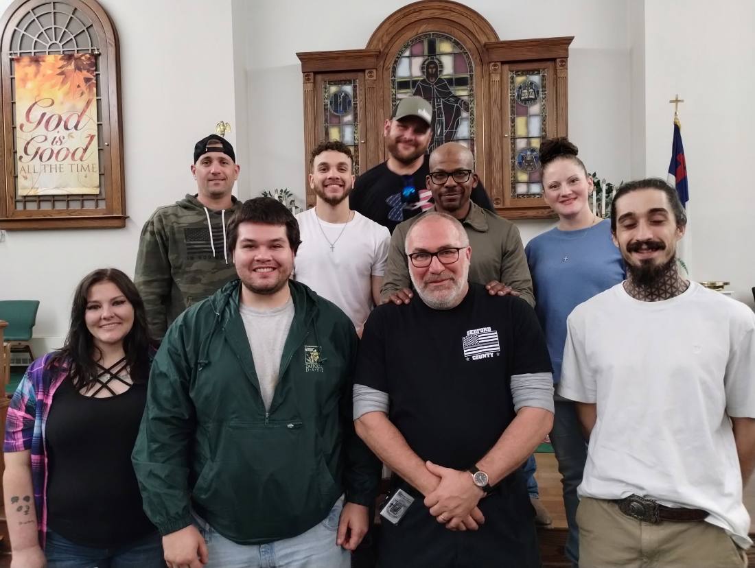 A group of former inmates and ministry volunteers standing together inside a church